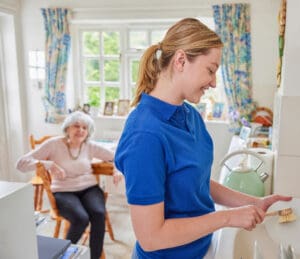 A female carer helps an elderly lady to wash up in the comfort of her own home