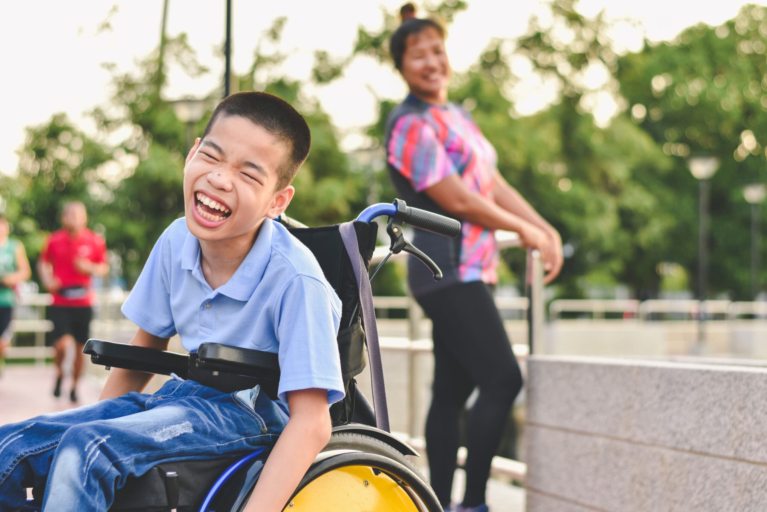 A smiling child in a wheelchair enjoys the sunshine