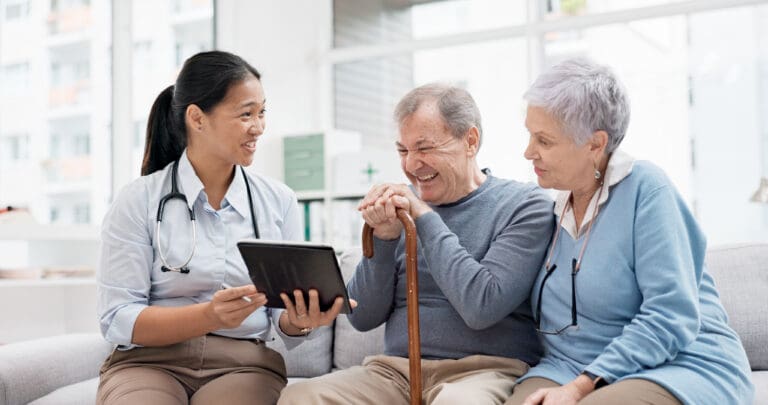 A couple look at a tablet with their healthcare professional