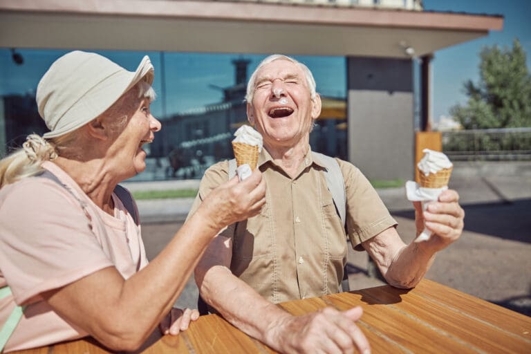 A happy older couple enjoy an ice cream in the sun