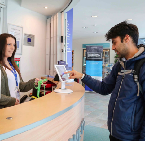 A man checks in as a visitor a care home using an e-reception tablet