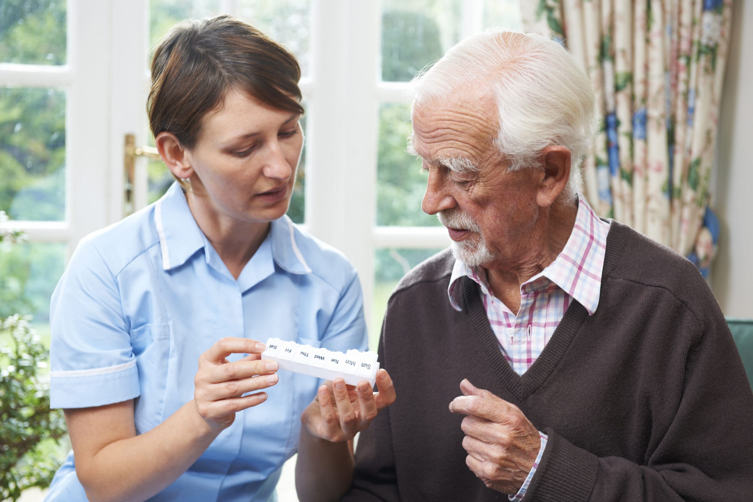 A carer helps an older man sort through his medication