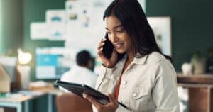 A woman speaks on the phone whilst looking at a tablet