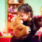 A little girl in a wheelchair hugs her teddybear